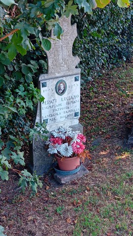 Cippo commemorativo a Cerati, dedicato a Luciano, con fiori e tributi.