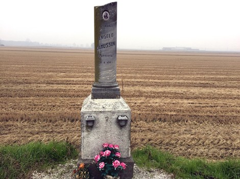 Cippo commemorativo a Camussoni, circondato da un campo in un'atmosfera avvolta dalla nebbia.