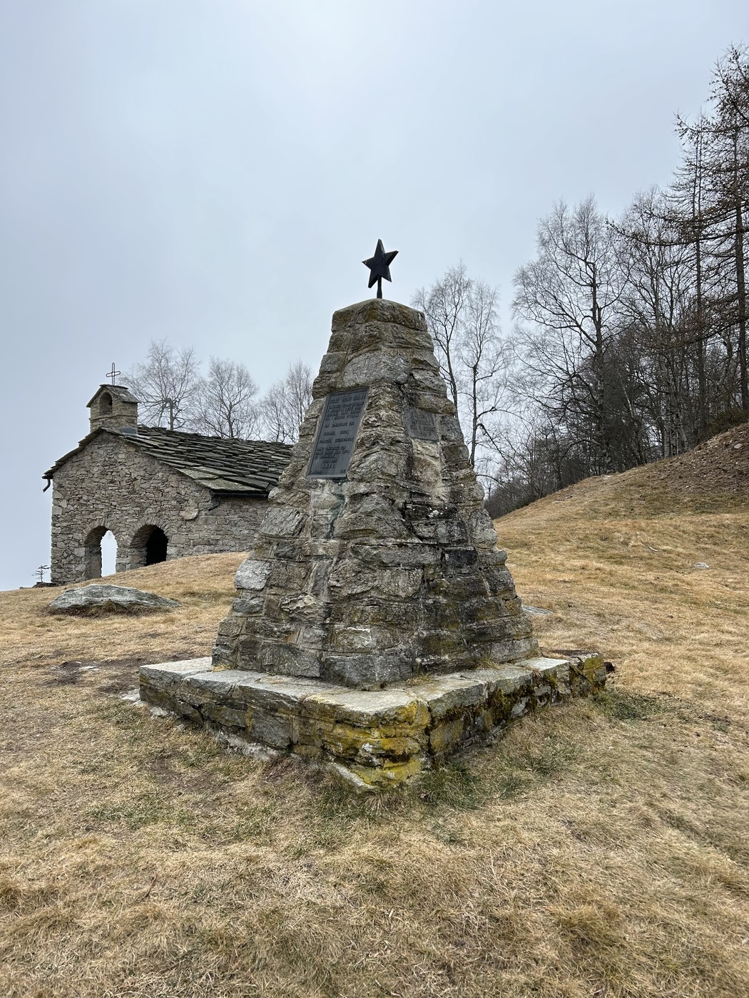 Monumento ai partigiani, commemorazione in pietra con stella, circondato da natura e storia.