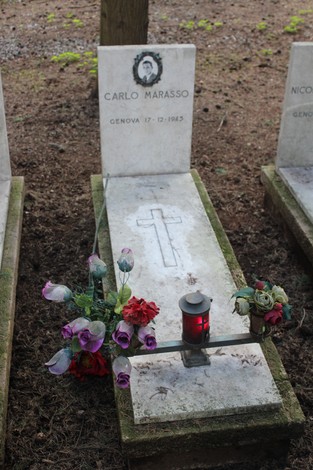 Tombe bianche con croce, fiori e una lanterna, dedicate ai caduti per la Libertà. Atmosfera raccolta e rispettosa.