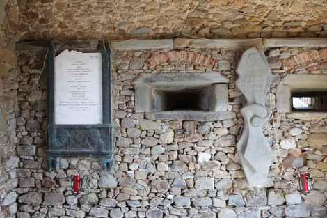 Lapide commemorativa dedicata ai caduti, incastonata in una parete di pietra.