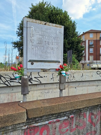 Lapide commemorativa in onore di Lavezzaro, Novelli e Zanotti, con fiori in omaggio.