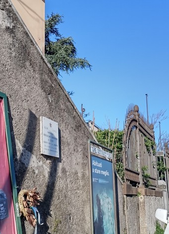 Targa che indica il nome "Barbieri" su un muro, con un cancello in stile decorativo sullo sfondo.