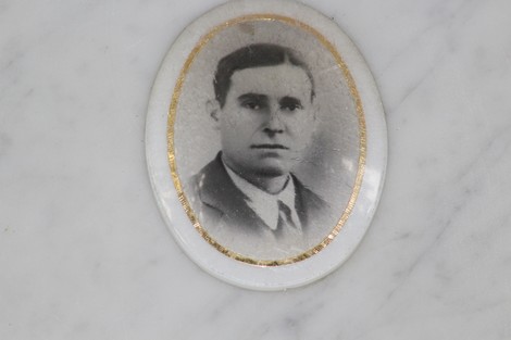 Un ritratto in bianco e nero di un uomo, incapsulato in una cornice ovale, affisso su una superficie marmorea.