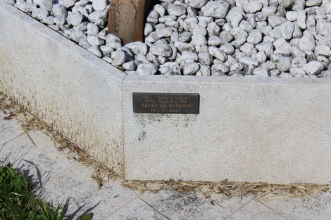Monumento a Cattoli, Frattini e Tomaselli, con base in pietra e ciottoli bianchi.