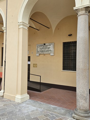 Lapide commemorativa dedicata ai caduti per la libertà, situata in un'area con architettura storica.