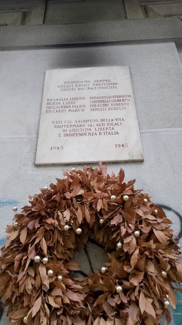 Lapide commemorativa dedicata a Basaglia, Beria e altri, con una corona di foglie decorative.