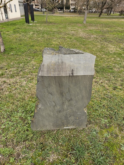 Monumento ai Partigiani, una pietra commemorativa in un parco, circondata da vegetazione.
