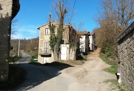 Immagine di un paesaggio rurale con case in pietra e sentieri, immerso nella natura.