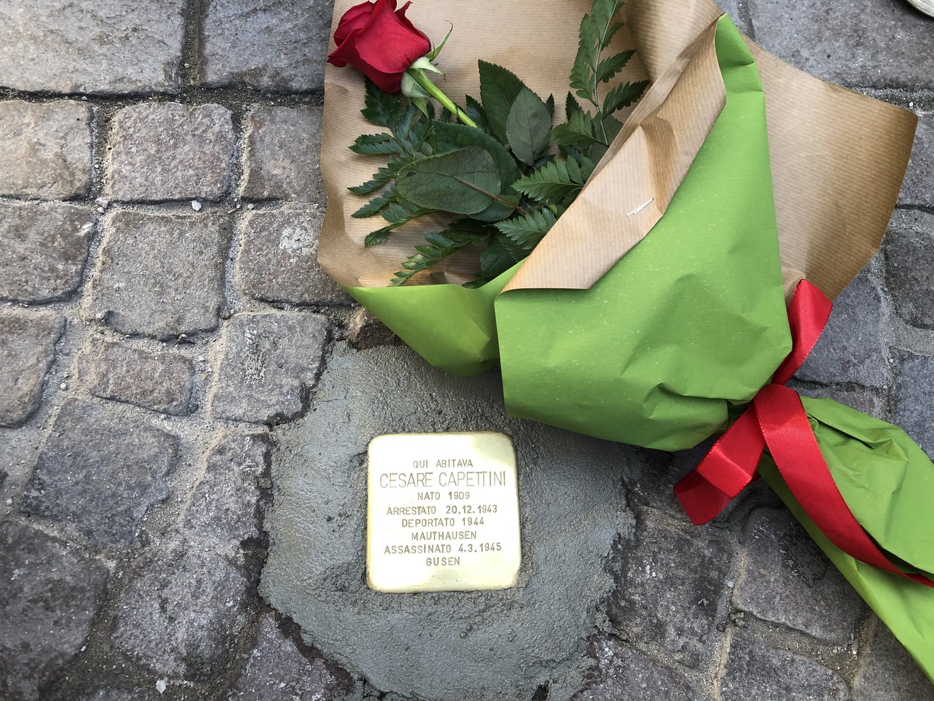 Pietra d'inciampo in commemorazione di Cesare Capettini, con fiori. Ricordo della sua persecuzione.