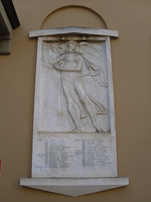 Lapide commemorativa ai caduti di Cavriago, con rilievo di un angelo e nomi degli amici e patrioti.