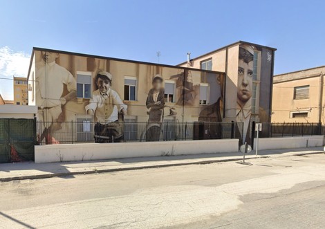 Murale che celebra la figura di Butera, con ritratti storici su un edificio in un contesto urbano.