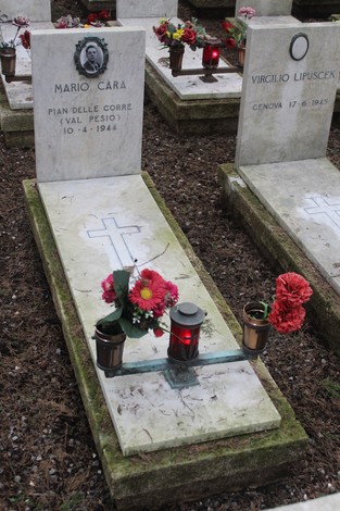 Tombe bianche decorate con fiori e candele, dedicate ai caduti per la Libertà. Atmosfera di commemorazione e rispetto.