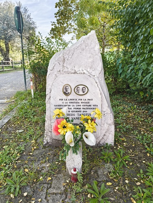 Cippo commemorativo dedicato a Tarozzi e ai Pinardi, con fiori e messaggi di pace.