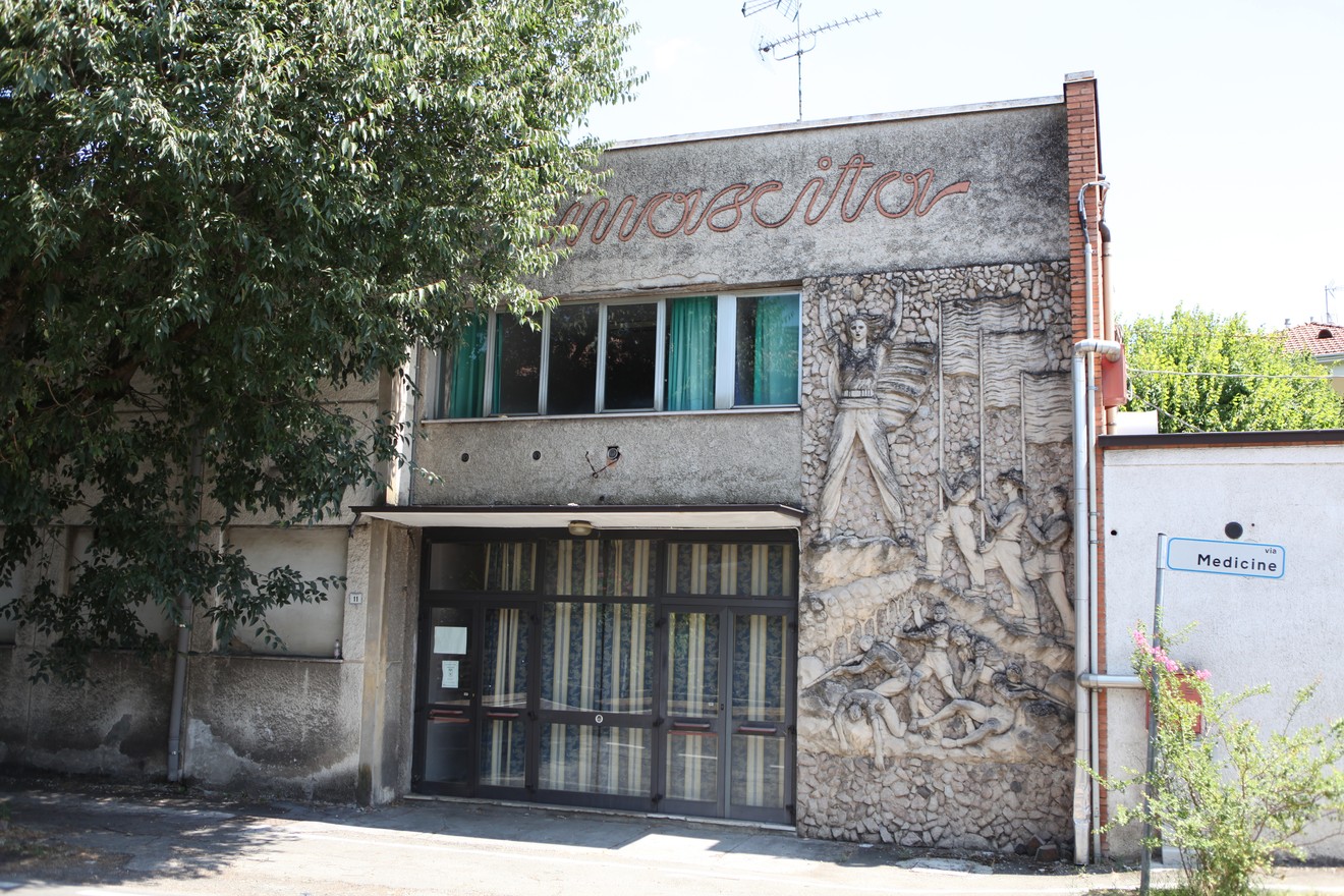 Bassorilievo decorativo sul muro di un edificio, rappresentante figure stilizzate in un contesto artistico.