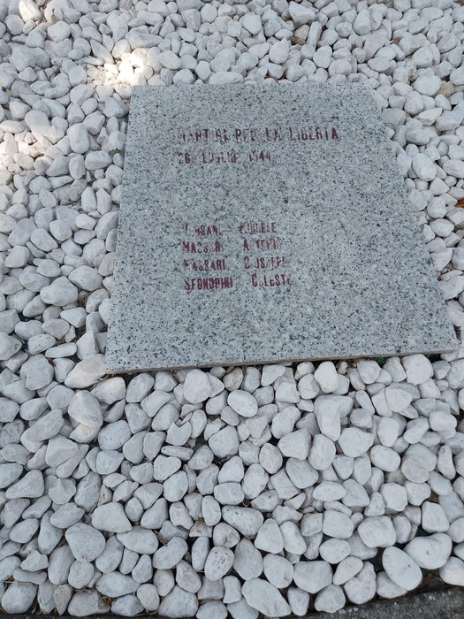 Monumento ai caduti per la Libertà, con una stele in pietra circondata da ghiaia bianca.