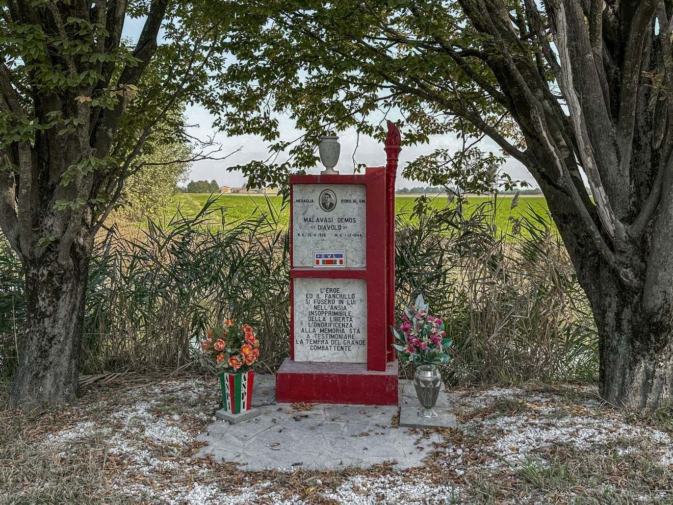 Monumento a Malavasi, commemorativo, immerso nella natura, circondato da fiori e alberi.
