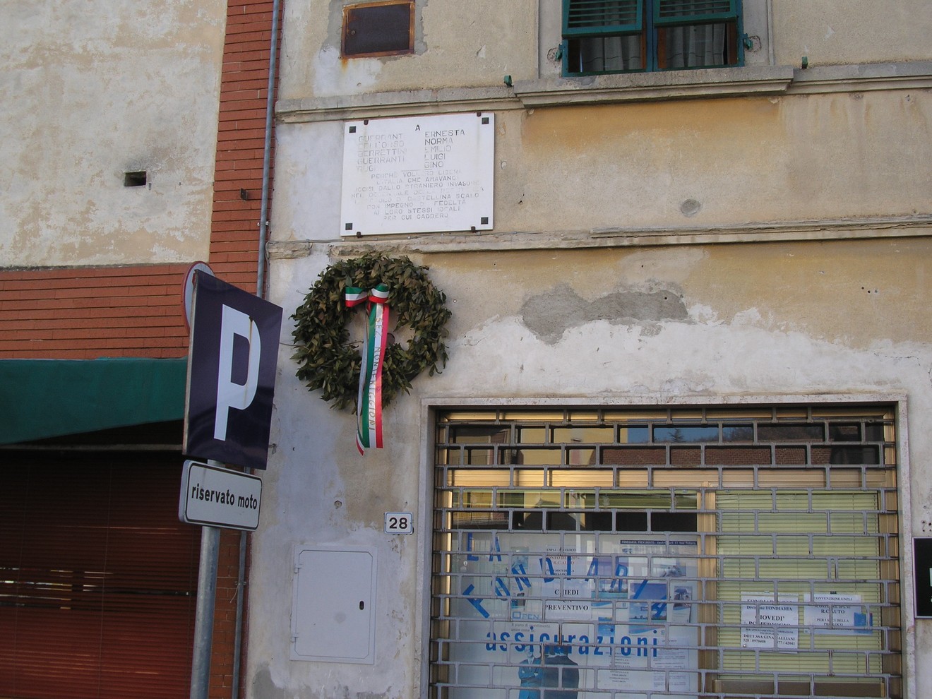 Lapide commemorativa a Castellina Scalo, con corona d'alloro e elementi decorativi.