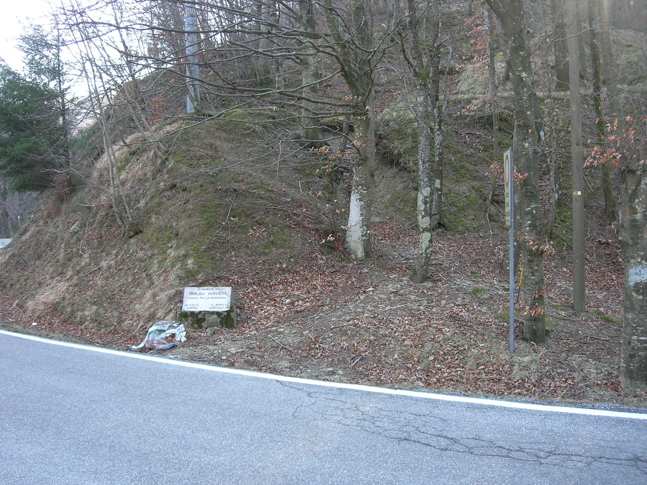 Cippo a Fantacci: monumento situato tra alberi, lungo una strada di montagna. Natura circostante in autunno.