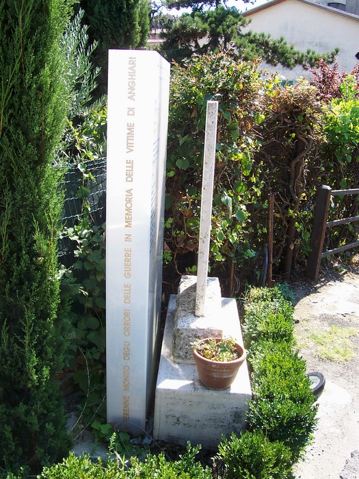 Monumento dedicato ai caduti del 18 Agosto, circondato da verde e simboli di commemorazione.