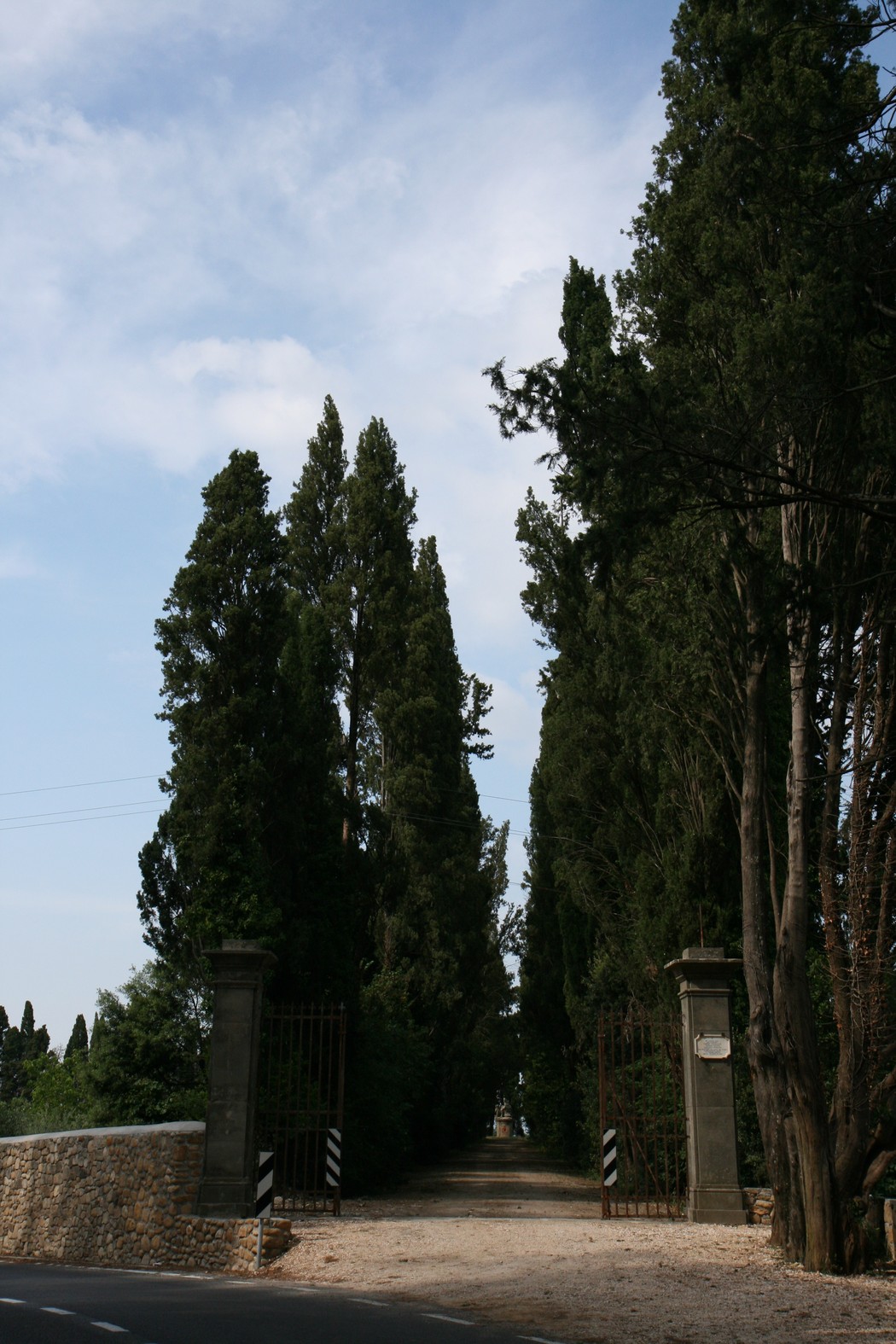 Accesso alla villa Le Corti, con viali fiancheggiati da cipressi e simmetria architettonica.