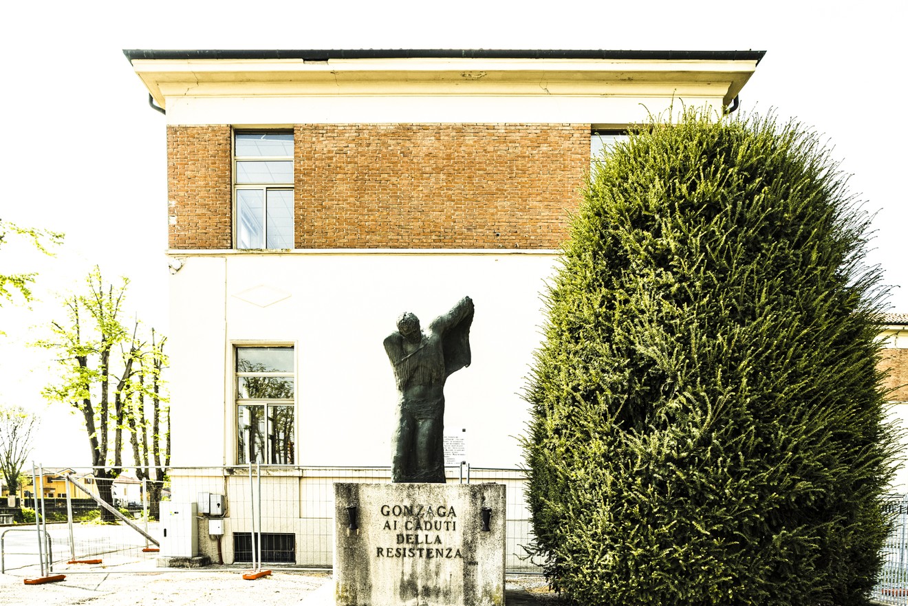 Monumento ai caduti della Resistenza, situato a Gonzaga, con una statua e una vegetazione circostante.