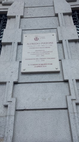 Lapide in pietra con iscrizione, fissata alla facciata di un edificio.