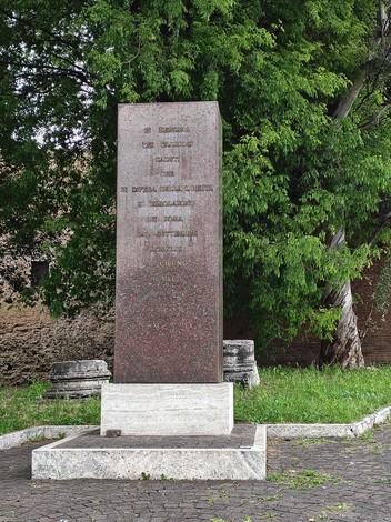 Monumento ai caduti per la Libertà, con una struttura in pietra circondata da verde e elementi architettonici.
