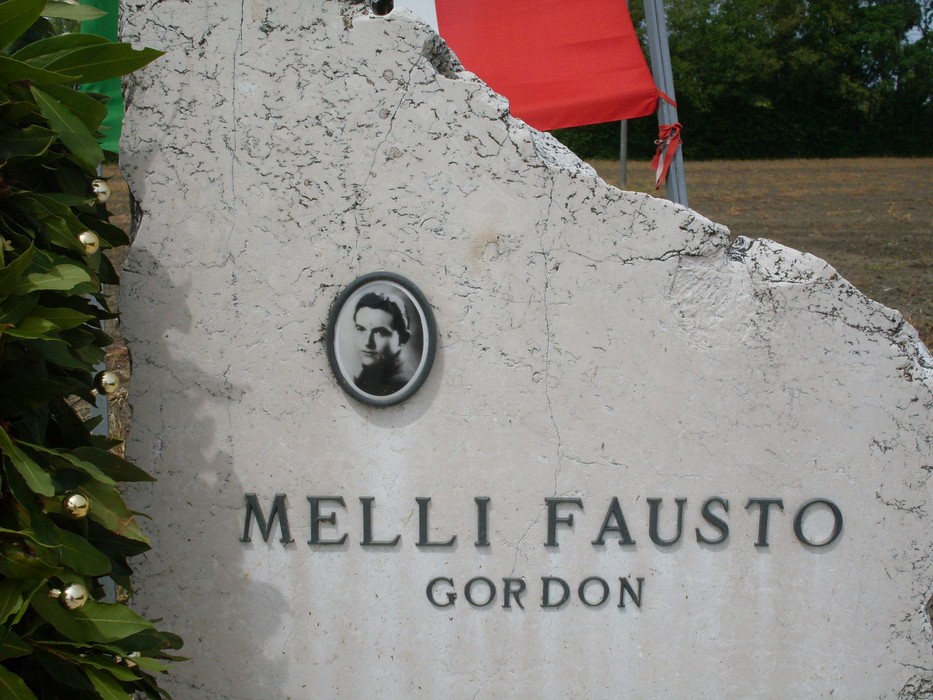 Cippo commemorativo dedicato a Fausto Melli, con foto e nome incisi sulla pietra.