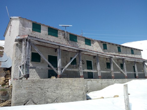 Targa informativa su edifici storici alle Baite di Abbio, immersi in un paesaggio montano.