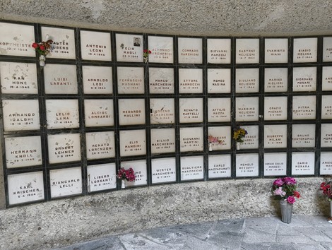 Monumento Ossario dedicato ai caduti partigiani, con lapidi commemorative e fiori.