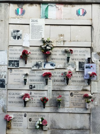 Sacrario ai martiri della libertà, con targhe commemorative e fiori, simbolo di memoria e dedizione.