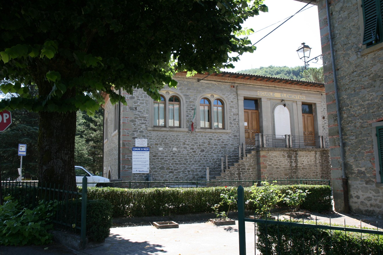 Lapide a Valentini, situata in un contesto storico con architettura tipica, circondata da verde.