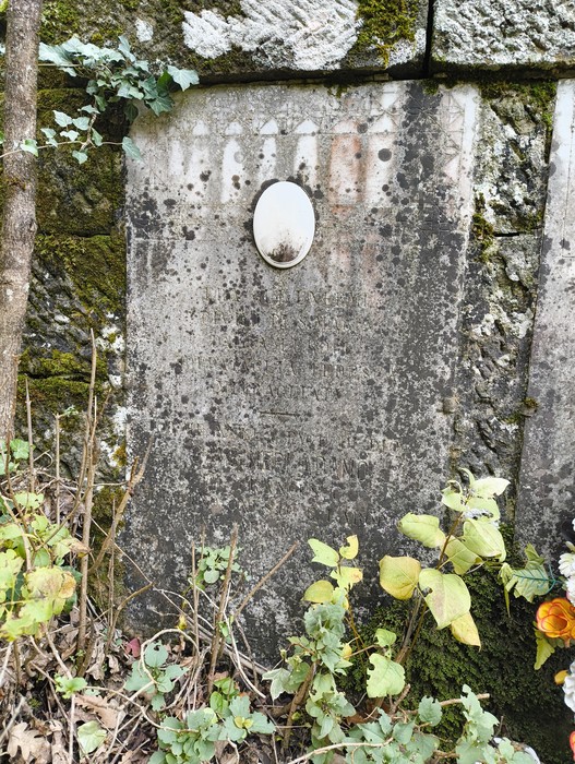 Sepolcri delle vittime di Giuncheto, con lapidi in pietra e decorazioni floreali nel contesto di un ambiente naturale.