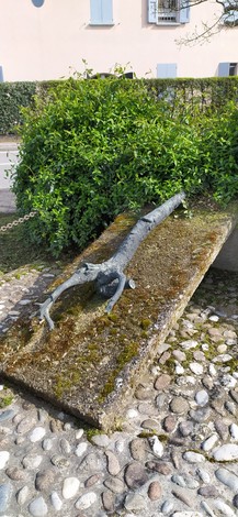 Stele commemorativa con un ramo inciso, immersa nel verde, in un contesto tranquillo di Le Budrie.