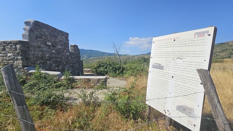Rovine di Ca' di Guzzo immerse nella natura, con un cartello informativo nelle vicinanze.