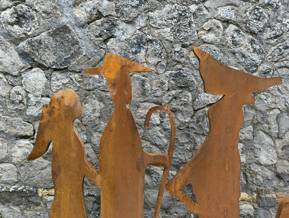 Statuette metalliche su uno sfondo di pietre, rappresentanti un gruppo che cammina.