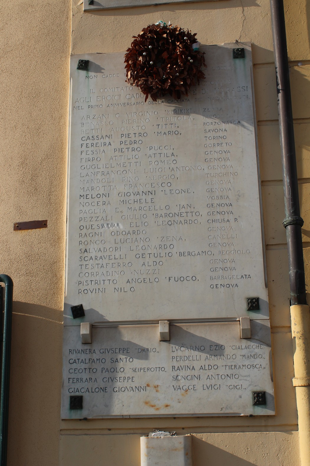 Lapide commemorativa ai caduti per la Libertà di Marassi, con nomi incisi e una corona di fiori.
