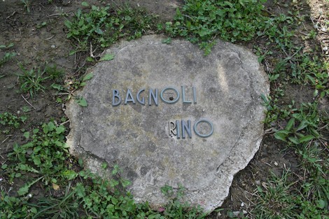 Monumento commemorativo nel cimitero di Stia, dedicato a Rino Bagnoli, immerso nel verde.