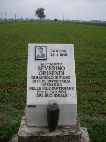 Cippo commemorativo dedicato a Severino Grisendi, caduto nella Seconda Guerra Mondiale, in un campo aperto.