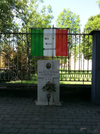 Cippo memoriale a Bellesia, con bandiera italiana e messaggio di resistenza.