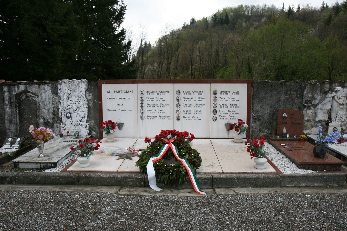 Tomba dei partigiani, commemorazione dei caduti, decorata con fiori e un tricolore italiano.