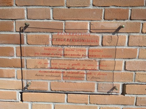 Targa commemorativa in vetro su muro di mattoni, dedicata alle donne deportate nei campi di concentramento.