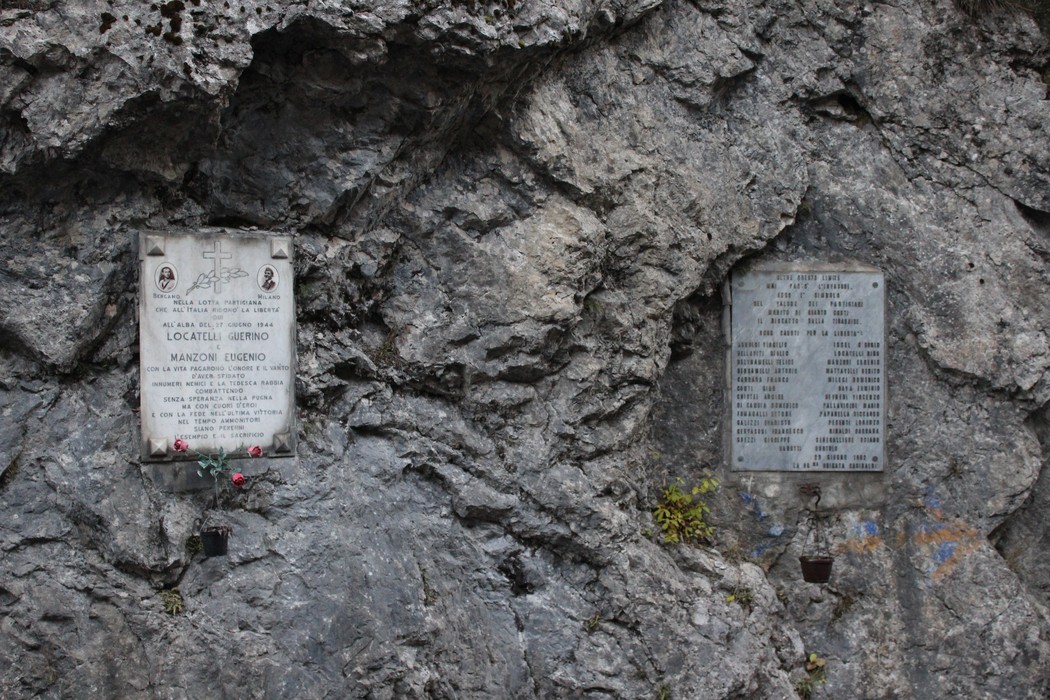 Lapide commemorativa dedicata a Locatelli e Manzoni affissa su un muro di roccia.