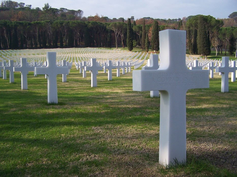 Cimitero Militare Americano con croci bianche in un vasto campo verde, simbolo di sacrificio e memoria.