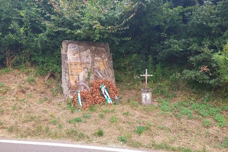 Monumento commemorativo dedicato a Moggi e Fissi, immerso nella vegetazione, con fiori e decorazioni tricolori.