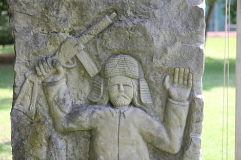 Monumento ai caduti per la libertà, con scultura di figura armata in rilievo su pietra.