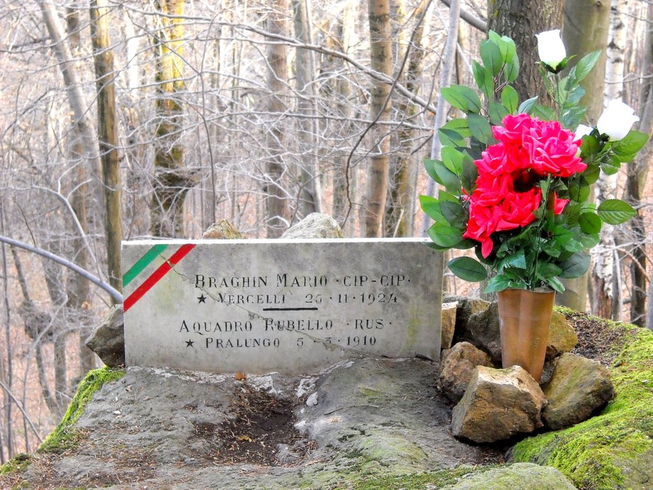 Lapide commemorativa con fiori dedicata a Braghin e Acquadro in un contesto naturale.