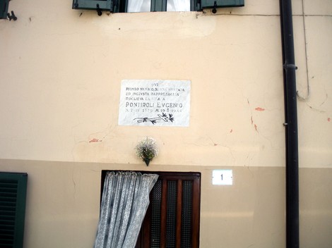 Lapide a Pontiroli, commemorativa, su una parete di un edificio, con decorazione floreale.