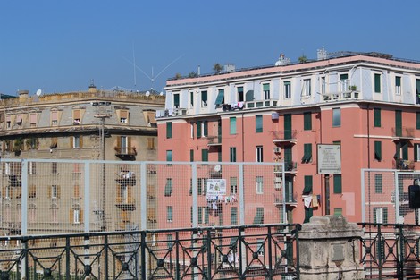 Lapide commemorativa su una facciata di un edificio, circondata da un paesaggio urbano colorato e luminoso.